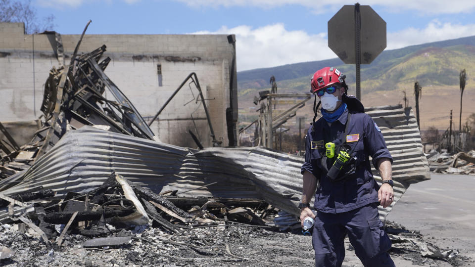 A member of a search-and-rescue team walks along a street, Saturday, Aug. 12, 2023, in Lahaina, Hawaii, following heavy damage caused by wildfires. (AP Photo/Rick Bowmer)