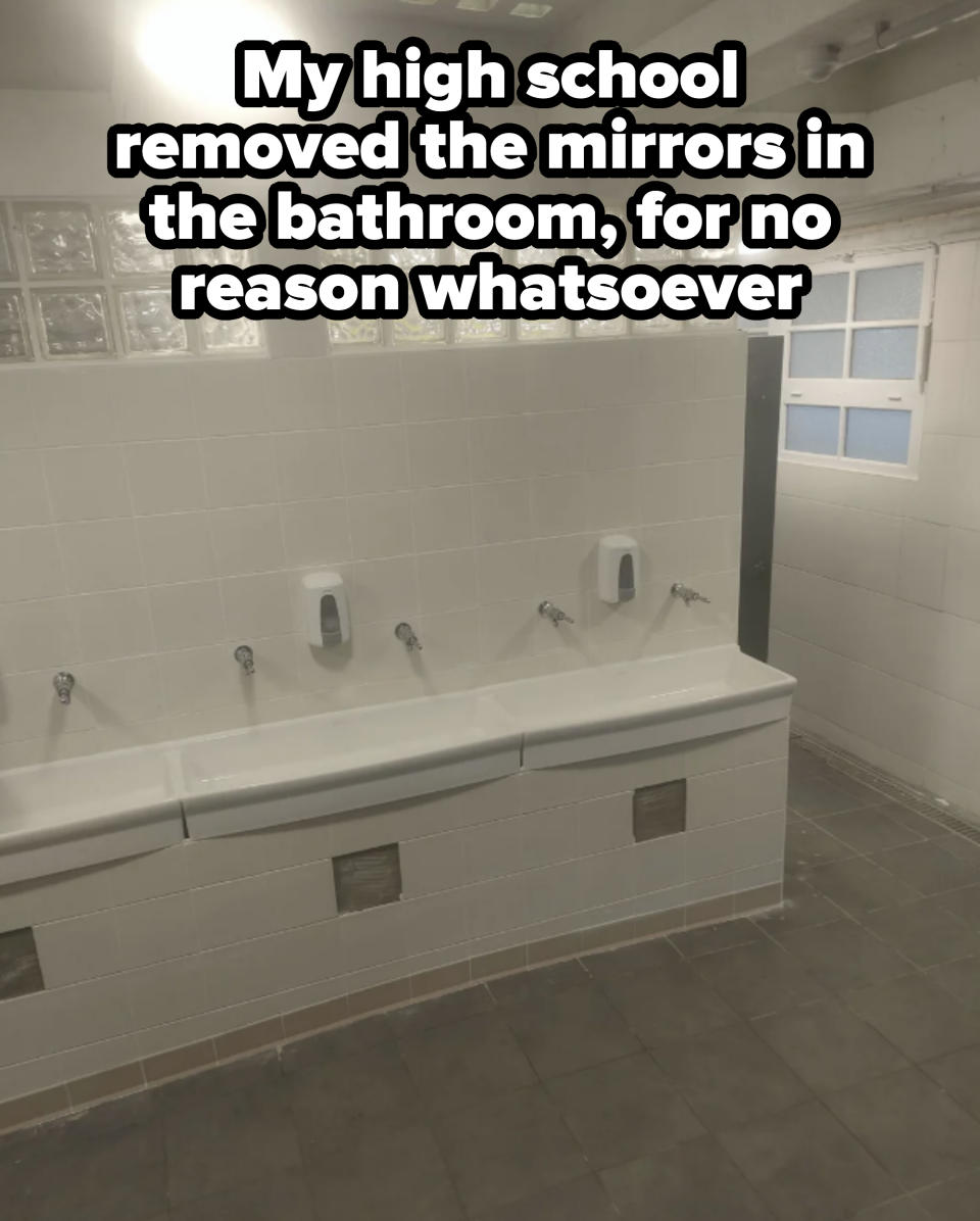 A modern public restroom with three sinks, each equipped with a soap dispenser, and a wall partially made of glass blocks. A window is in the background