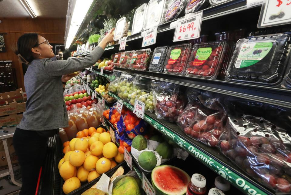 Madison Tanthongsack restocks the fruit and produce at Seven Grains Natural Market in Tallmadge April 14.