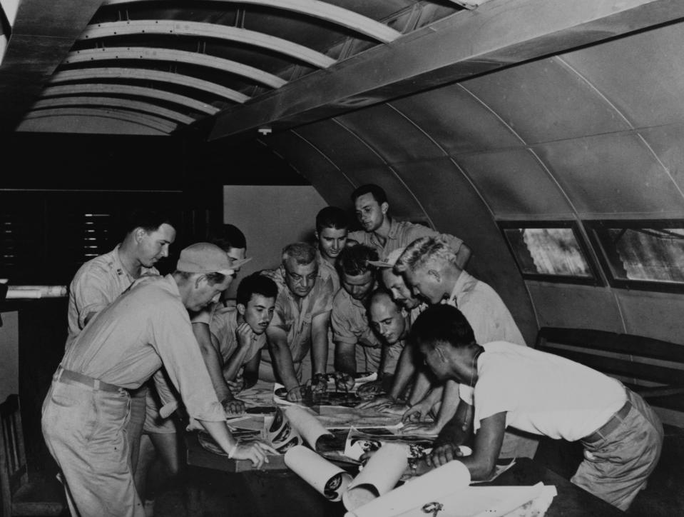 The flight crews of two planes go over planes for the dropping of the first atomic bombs. The middle-aged man in the center is Lt. Col. Payette. On the left, in the foreground in profile is Lt. Ralph Devore. The man looking over Payette’s shoulder is Major Chuck Sweeney. Sweeney commanded and Devore flew with the mission to drop the second bomb on Nagasaki. To the right in profile are Lts. Thomas Ferebee (in cap, with mustache) and Morris Jeppson, both of whom flew with the first mission to bomb Hiroshima. (Photo: Corbis via Getty Images)