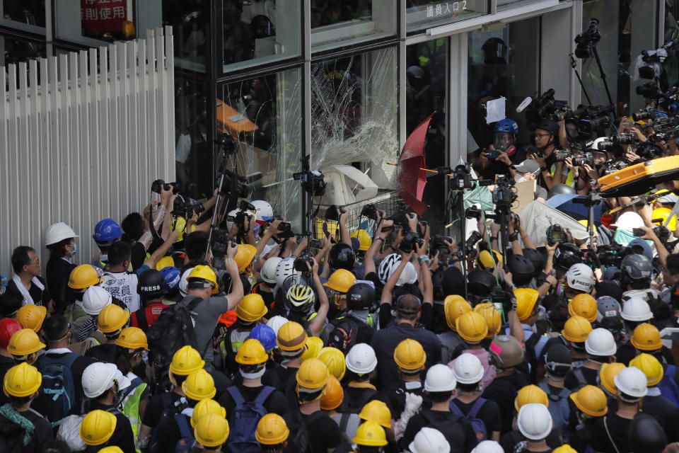 In this photo taken July 1, 2019, protesters use a cart to break through the glass panel of the Legislative Council in Hong Kong. A pro-democracy lawmaker who tried to stop Hong Kong protesters from breaking into the legislature says China will likely use the vandalizing of the building as a reason to step up pressure on the semi-autonomous territory. (AP Photo/Kin Cheung)