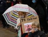 A child holds up a a poster of Samuel Paty as people gather on Republique square in Lille, northern France, Sunday Oct. 18, 2020. Demonstrators in France on Sunday took part in gatherings in support of freedom of speech and in tribute to a history teacher who was beheaded near Paris after discussing caricatures of Islam’s Prophet Muhammad with his class. (AP Photo/Michel Spingler)