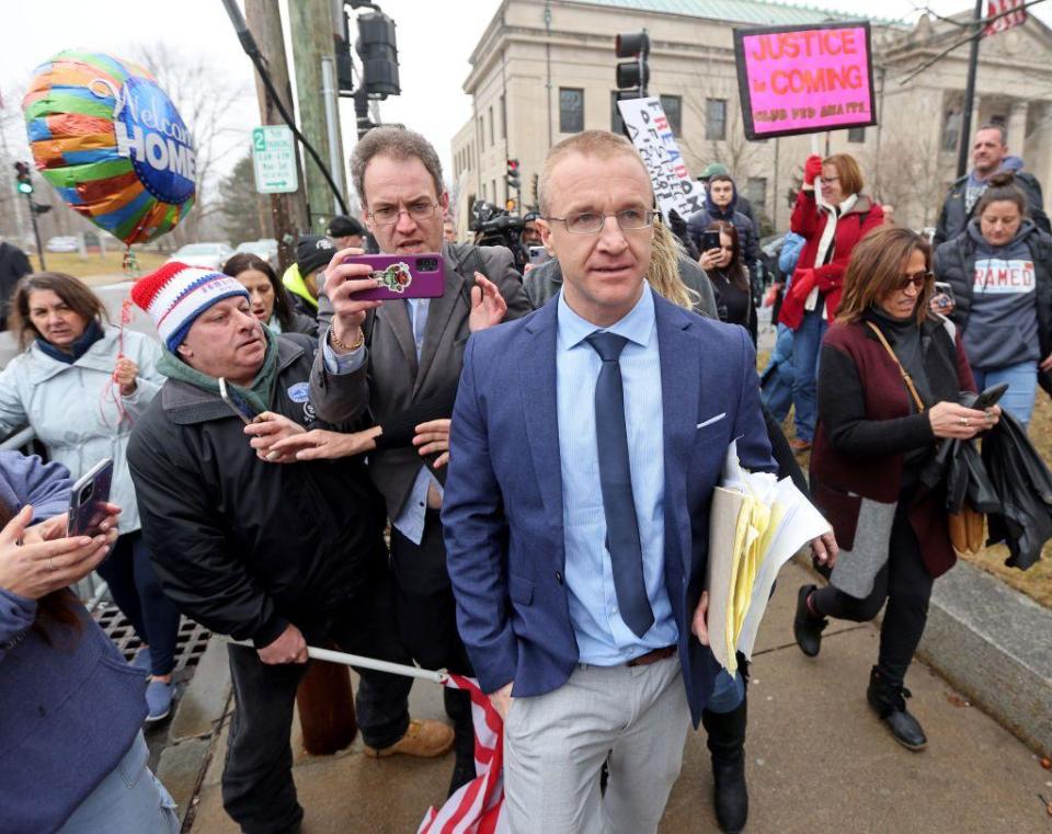 Aidan Kearney walks away from court with papers in his hands as a crowd follows him