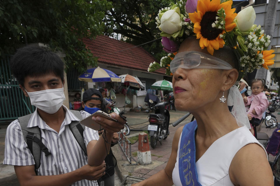 Cambodian-American lawyer Theary Seng, dressed in a pageant costume that reads "Lady Justice", talks to media outside Phnom Penh Municipal Court in Phnom Penh, Cambodia, Tuesday, May 3, 2022. Tuesday is the the final day of hearings for her trial on treason and a related charge for which she could receive a prison sentence of up to 12 years. (AP Photo/Heng Sinith)