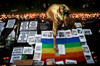 <p>A man places a doll beside candles, flowers and photos of victims of the gay nightclub mass shooting in Orlando, at St Anne’s Church in the Soho district of London on June 13, 2016. (Photo: Dylan Martinez/Reuters) </p>