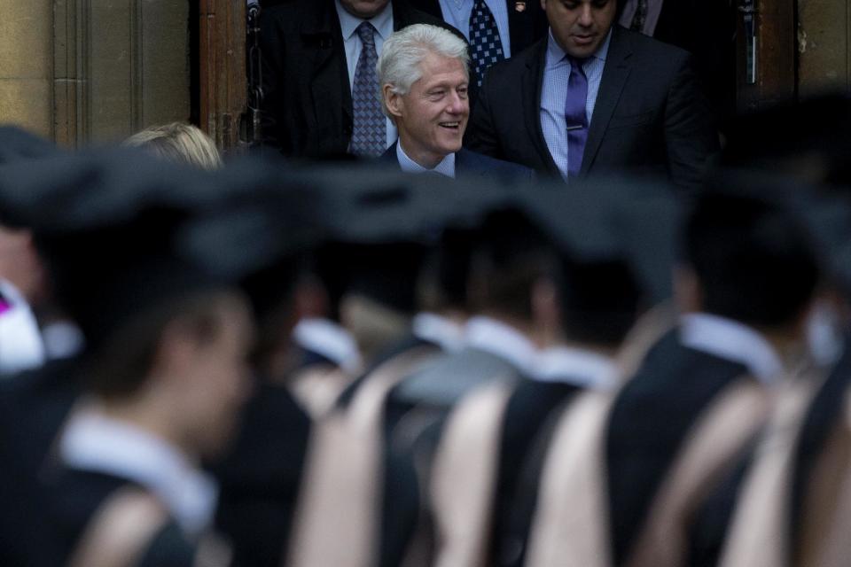 Students in their graduation gowns and caps stand in the foreground as former U.S. President Bill Clinton, center, and his wife former Secretary of State Hillary Rodham Clinton, left obscured, leave after they attended their daughter Chelsea's Oxford University graduation ceremony held at the Sheldonian Theatre in Oxford, England, Saturday, May 10, 2014. Chelsea Clinton received her doctorate degree in international relations on Saturday from the prestigious British university. Her father was a Rhodes scholar at Oxford from 1968 to 1970. The graduation ceremony comes as her mother is considering a potential 2016 presidential campaign. (AP Photo/Matt Dunham)