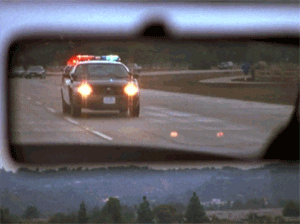 Police car with flashing lights viewed from rearview mirror