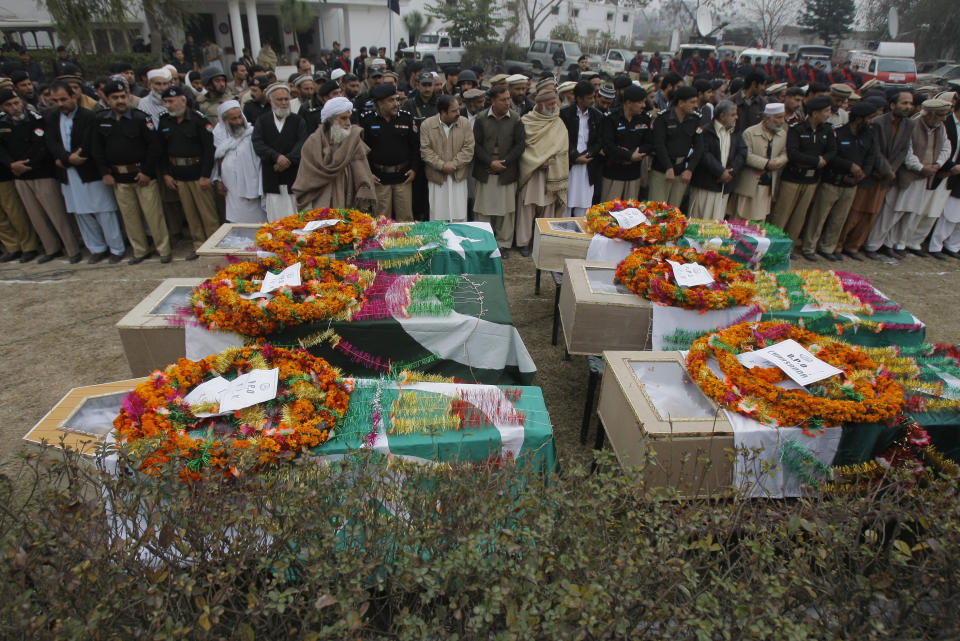 Pakistani police officers, and relatives of six policemen who were killed from a bomb explosion, pray in front of their coffins, during their funeral procession in Charsadda, Pakistan, Wednesday, Jan. 22, 2014. A bomb rigged to a bicycle struck a police patrol on its way to guard a polio vaccination team in northwestern Charsadda district, killing six, said officer Shafiullah Khan. (AP Photo/Mohammad Sajjad)