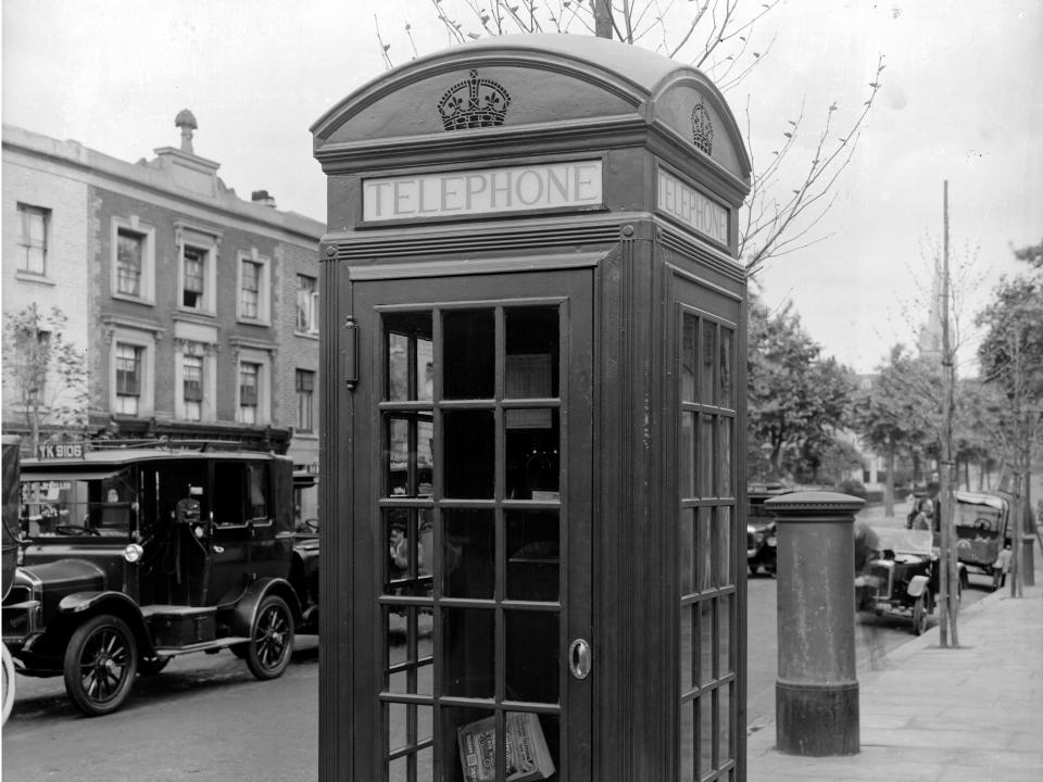 An individual phone booth with windows on the sidewalk.