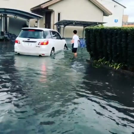 A car drives through floodwaters after heavy rains in Mizugae