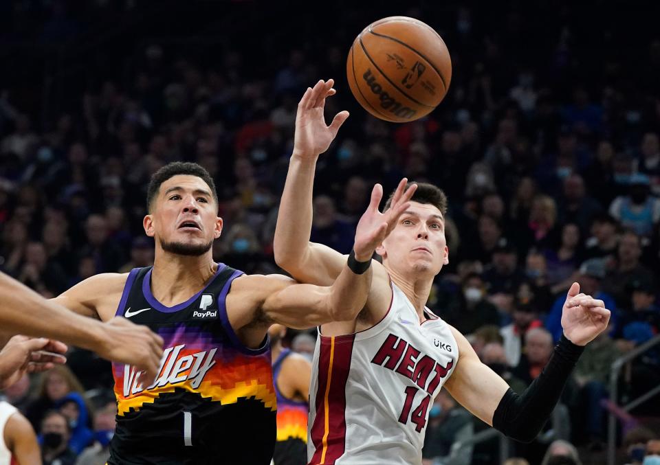 Phoenix Suns' Devin Booker (1) battles for the ball with Miami Heat's Tyler Herro (14) during the first half of an NBA basketball game Saturday, Jan. 8, 2022, in Phoenix. (AP Photo/Darryl Webb)