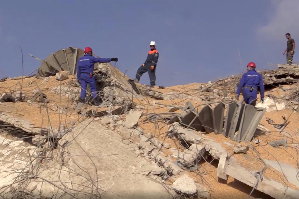 En esta imagen, tomada de un video distribuido por el servicio de prensa del Ministerio de Situaciones de Emergencia de Rusia, efectivos del departamento caminan entre los restos de una explosión en el puerto de Beirut, Líbano, el 6 de agosto de 2020. (AP Foto/Servicio de prensa del Ministerio de Situaciones de Emergencia vía AP)