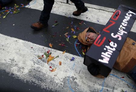 A demonstrator lays on the ground with a chalk outline to represent a mock crime scene during a protest marking the 100th day since the shooting death of Michael Brown in St. Louis, Missouri November 16, 2014. REUTERS/Jim Young