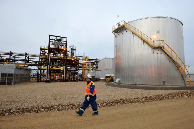 FILE PHOTO: An oilfield worker walks past an oil sands facility