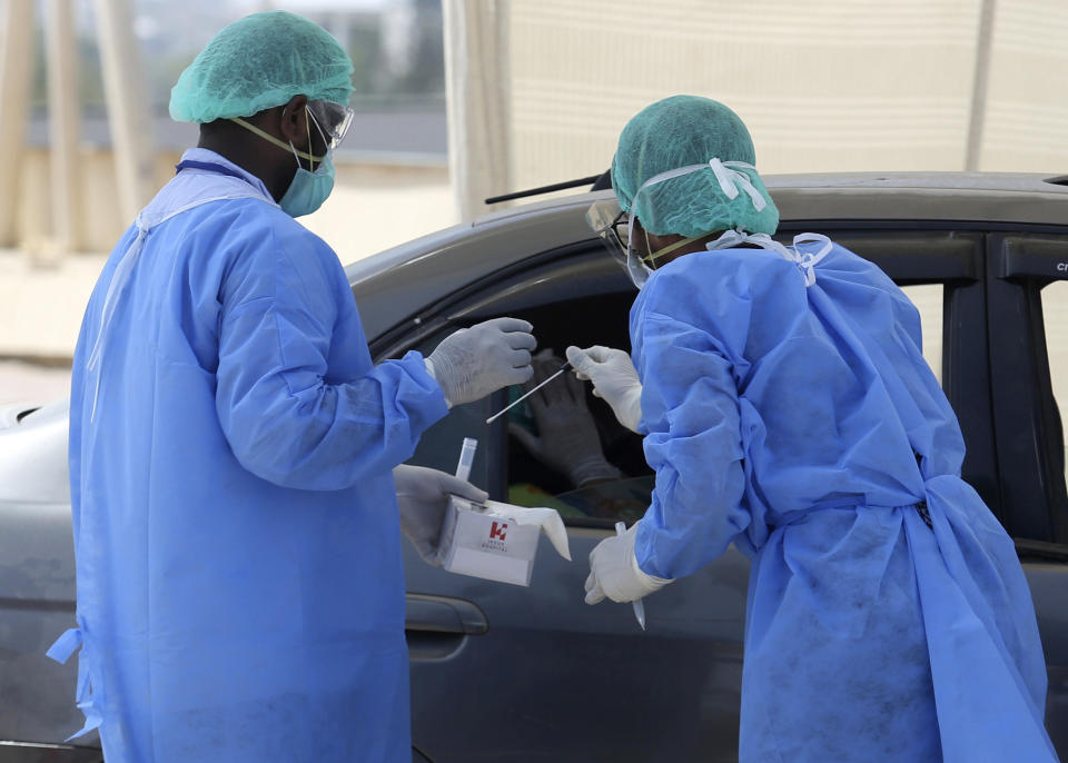 Health workers collect a specimen at a drive-thru testing and screening facility for the coronavirus, in Karachi, Pakistan, Monday, April 6, 2020. Authorities in Pakistan's Sindh province established the first ever drive-thru coronavirus testing facility in Pakistan as part of to control the spread of pandemic coronavirus in the province. (AP Photo/Fareed Khan)