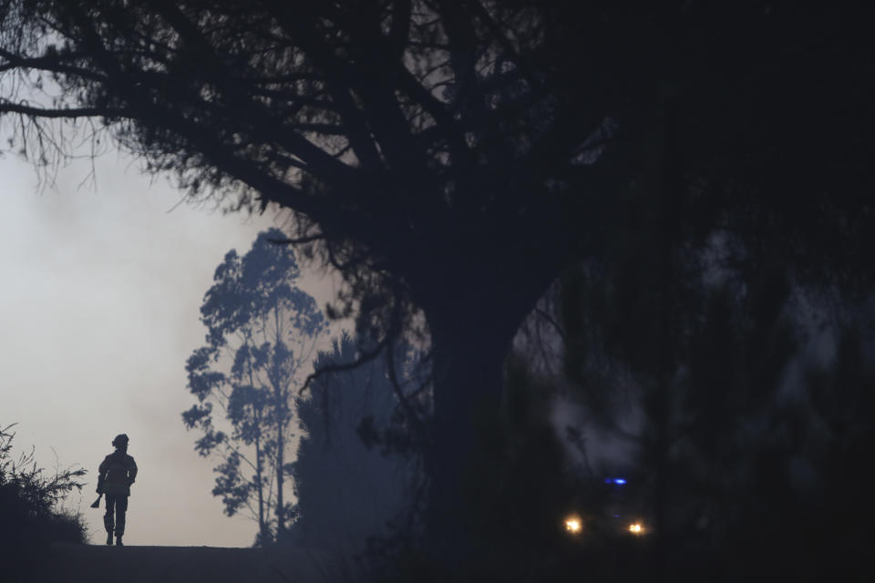 A firefighter walks near a forest fire in the Rio Maior area in Portugal, Wednesday, Aug. 17, 2022. Authorities in Portugal said they hoped to bring under control a wildfire that has burned for 12 days and burnt large swaths of pine forest in the Serra da Estrela Natural Park. However, officials warned a new heat wave forecast for the area could complicate the task. (AP Photo/Joao Henriques)