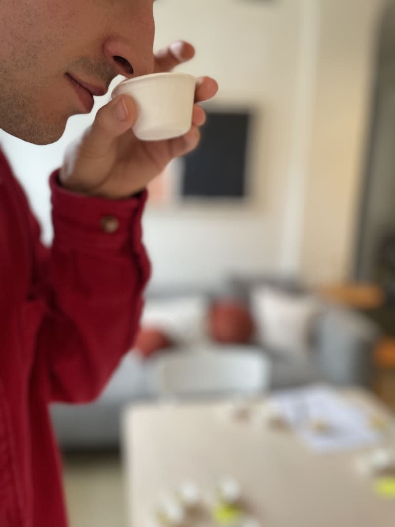 Person with nose up to small white cup