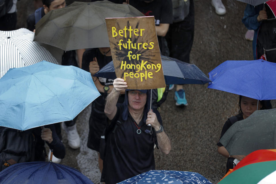 A man displays a placard as protesters gather in Hong Kong Sunday, Aug. 18, 2019. Heavy rain fell on tens of thousands of umbrella-ready protesters as they started marching from a packed park in central Hong Kong, where mass pro-democracy demonstrations have become a regular weekend activity. (AP Photo/Vincent Thian)