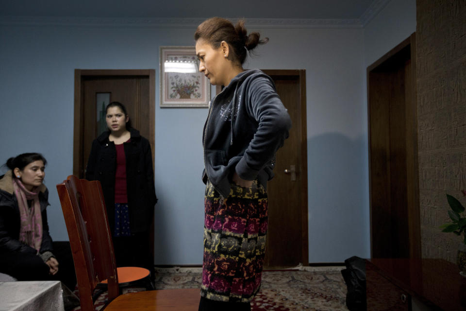 Guzaili Nu'er, wife of Ilham Tohti, right, pauses next to her husband's students at her house in Beijing Thursday, Jan. 16, 2014. Police have taken away Ilham Tohti, an outspoken scholar of China's Turkic Uighur ethnic minority and raided his home, seizing computers, cellphones and even his students' theses, his wife said Thursday. (AP Photo/Andy Wong)