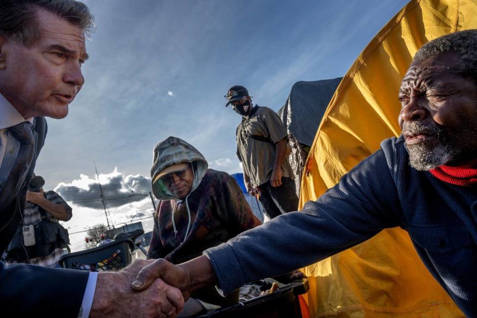 La leyenda del beisbol Steve Garvey estrecha la mano de Lavell Wright, de 66 años, en un campamento de personas sin hogar en Sacramento, el miércoles 17 de enero de 2024. Garvey, un candidato republicano al Senado federal, dijo que quiere rendición de cuentas sobre cómo se gasta el dinero para ayudar a los indigentes.