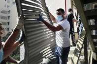 FILE - In this August 7, 2020 file photo, people remove debris from the damaged Rosary Sisters Hospital in a neighborhood near the scene of the Aug. 4 explosion that hit the seaport of Beirut, Lebanon. Eight hospitals and 20 clinics sustained partial or heavy structural damage and two hospitals remain largely out of service. The cost of repairs is estimated at nearly $30 million, the World Health Organization said. (AP Photo/Thibault Camus, File)