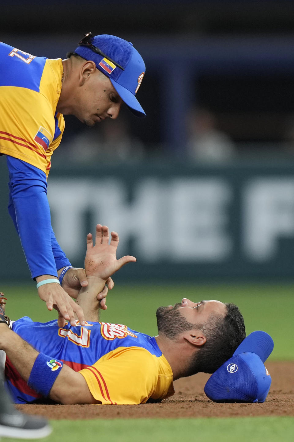 Venezuela second baseman Jose Altuve (27) is helped up by short stop Andres Gimenez (0) after he was upended by U.S.'s Trea Turner during a double play in the second inning of a World Baseball Classic game, Saturday, March 18, 2023, in Miami. Mookie Betts was out at first. (AP Photo/Wilfredo Lee)