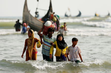 Rohingya refugees walk to the shore with his belongings after crossing the Bangladesh-Myanmar border by boat through the Bay of Bengal in Teknaf, Bangladesh,. REUTERS/Mohammad Ponir Hossain