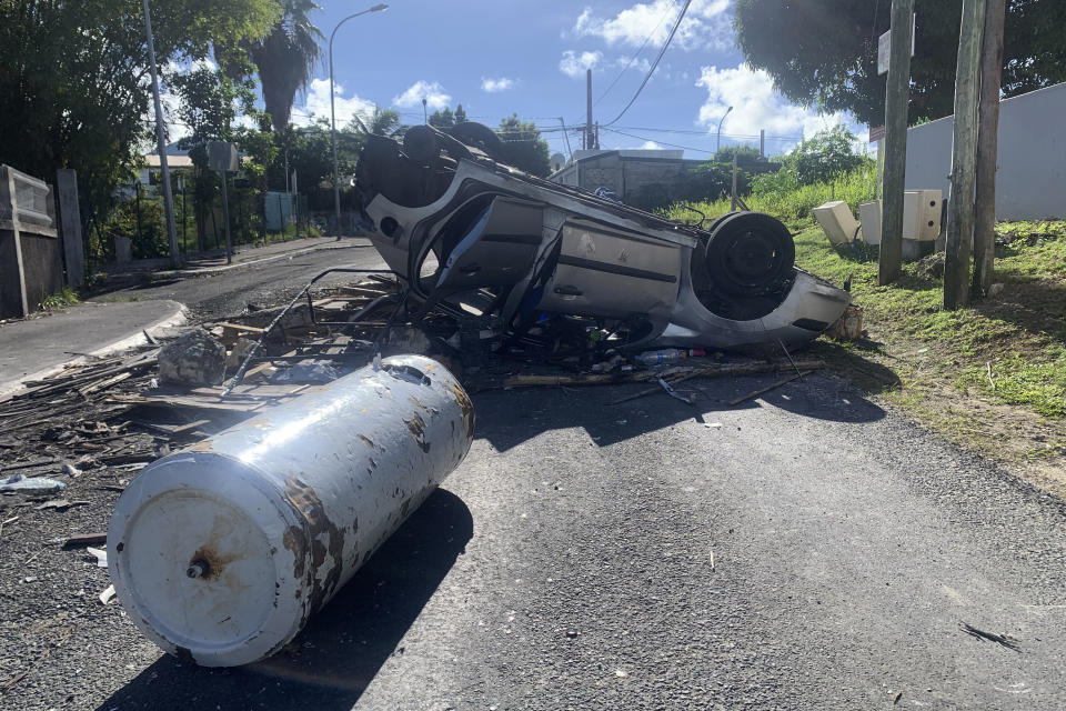 An overturned car is pictured in a s street of Le Gosier, Guadeloupe island, Sunday, Nov.21, 2021. French authorities are sending police special forces to the Caribbean island of Guadeloupe, an overseas territory of France, as protests over COVID-19 restrictions erupted into rioting. The protests have been called for by trade unions to denounce the COVID-19 health pass that is required to access restaurants and cafes, cultural venues, sport arenas and long-distance travel. (AP Photo/Elodie Soupama)