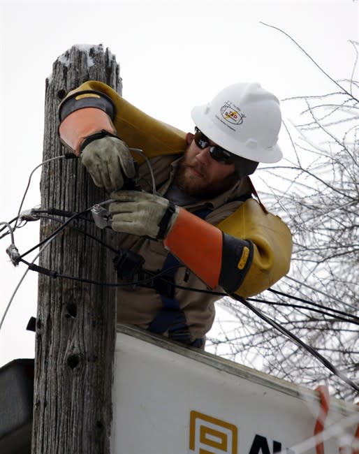 Cory Bean works atop a utility pole to repair a power line, Thursday, Dec. 26, 2013, in East Lansing, Mich. Bean is part of a crew from utility service company T&D Solutions out of Kentucky brought in to assist Consumers Energy with restoring power in Michigan after an ice storm. Bean has been working in Michigan since Sunday. (AP Photo/Al Goldis)