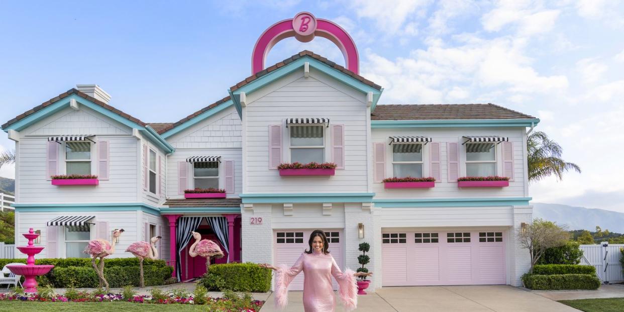 host ashley graham poses in front of the finished barbie dream house, as seen on barbie dream house challenge, season 1