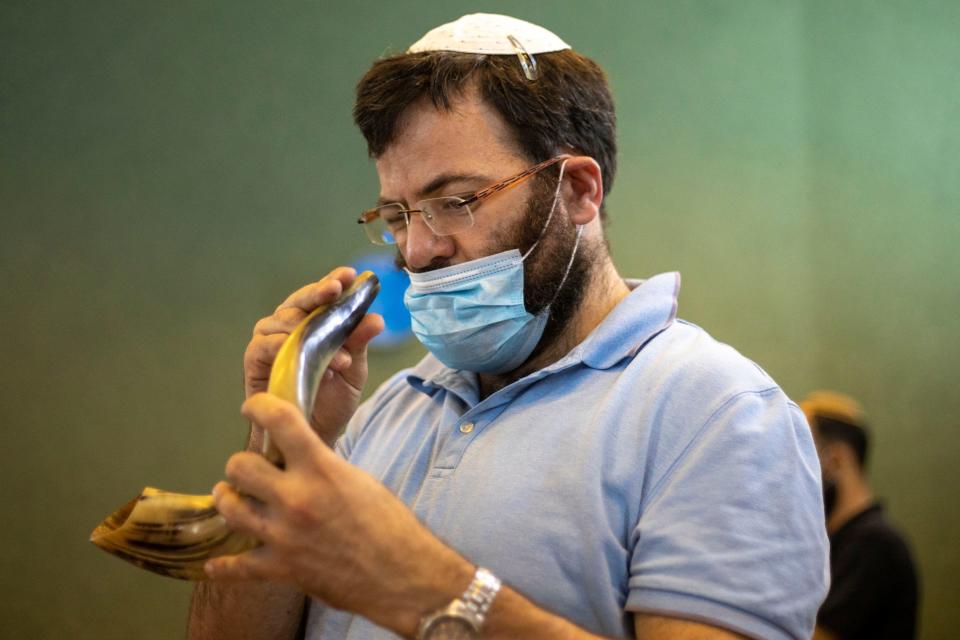 A man in Tel Aviv examines a shofar, a horn that is traditionally blown on Rosh Hashanah. This year, people are bringing their shofars outside to observe the holiday.