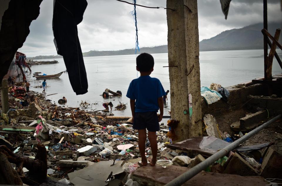 A boy peers out of a damaged structure near the shoreline on November 23, 2013 in Tacloban, Leyte, Philippines. Bodies continue to be recovered nearly two weeks after the devastating Typhoon Haiyan hit as the official death toll now exceeds 5,000. The typhoon has been described as one of the most powerful to ever to hit land, leaving thousands dead and hundreds of thousands homeless. Countries all over the world have pledged relief aid to help support those affected by the typhoon, but damage to the airport and roads have made moving the aid into the most affected areas very difficult.