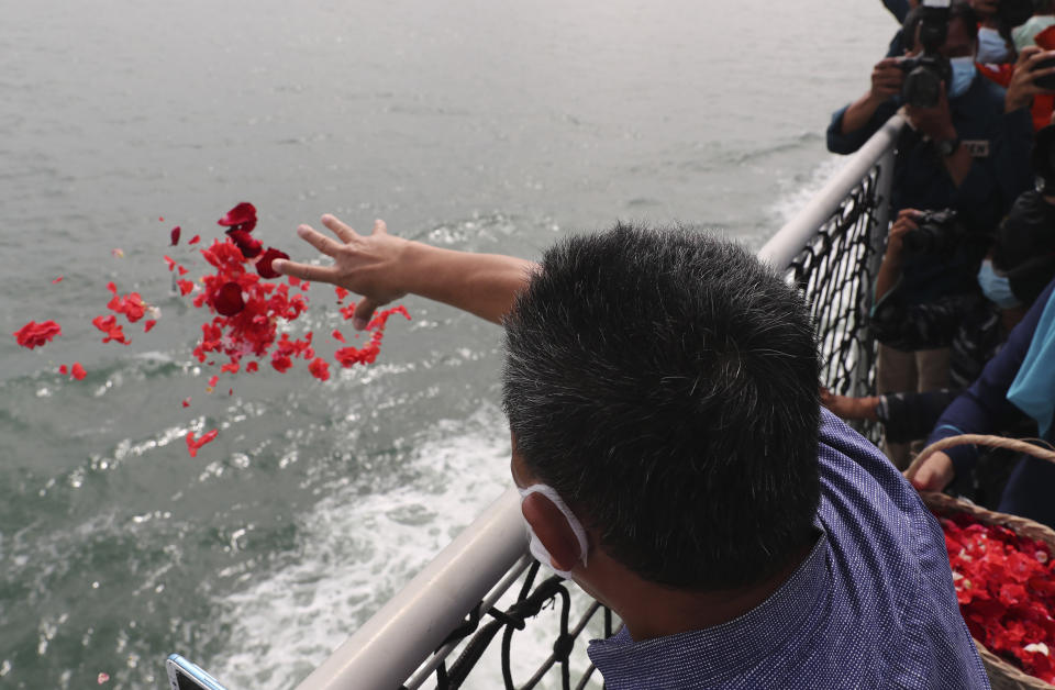 A relative of the victims of Sriwijaya Air flight SJ-182 throw flowers into the Java Sea where the plane crashed on Jan. 9 killing all of its passengers, during a memorial ceremony held on the deck of Indonesian Navy Ship KRI Semarang, near Jakarta in Indonesia, Friday, Jan. 22, 2021. (AP Photo/Tatan Syuflana)