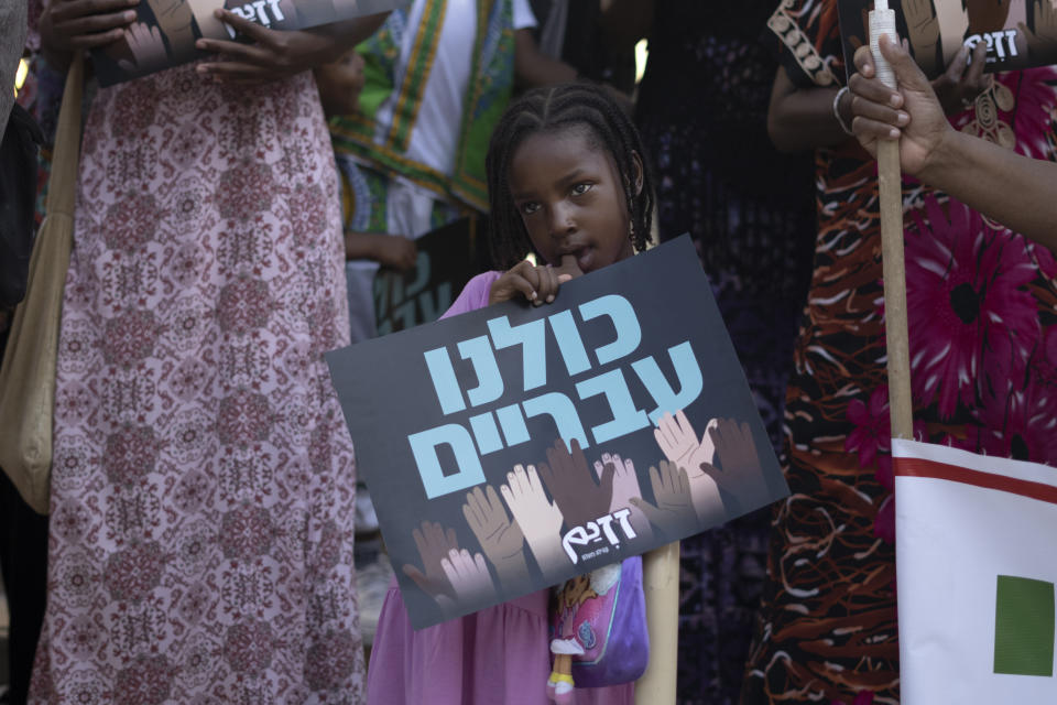 A child from the African Hebrew Israelites of Jerusalem holds a placard that reads "we are all Hebrew," at a rally outside of the District Court in Beersheba, Israel, ahead of a hearing on the deportation orders dozens from their community, Wednesday, July 19, 2023. The community first made their way to Israel from the United States in the 1960s. While they do not consider themselves Jewish, they claim an ancestral connection to Israel. (AP Photo/Maya Alleruzzo)