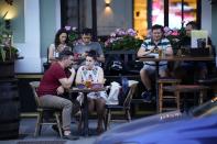 People sit in an open veranda of a restaurant in Moscow, Russia, Thursday, June 24, 2021. An ambitious plan of vaccinating 30 million Russians by mid-June against the coronavirus has fallen short by a third, and the country has started to see a surge in daily new infections. So now, many regional governments across the vast country are obligating some workers to get vaccinated and requiring the shots to enter certain businesses, like restaurants. (AP Photo/Alexander Zemlianichenko)