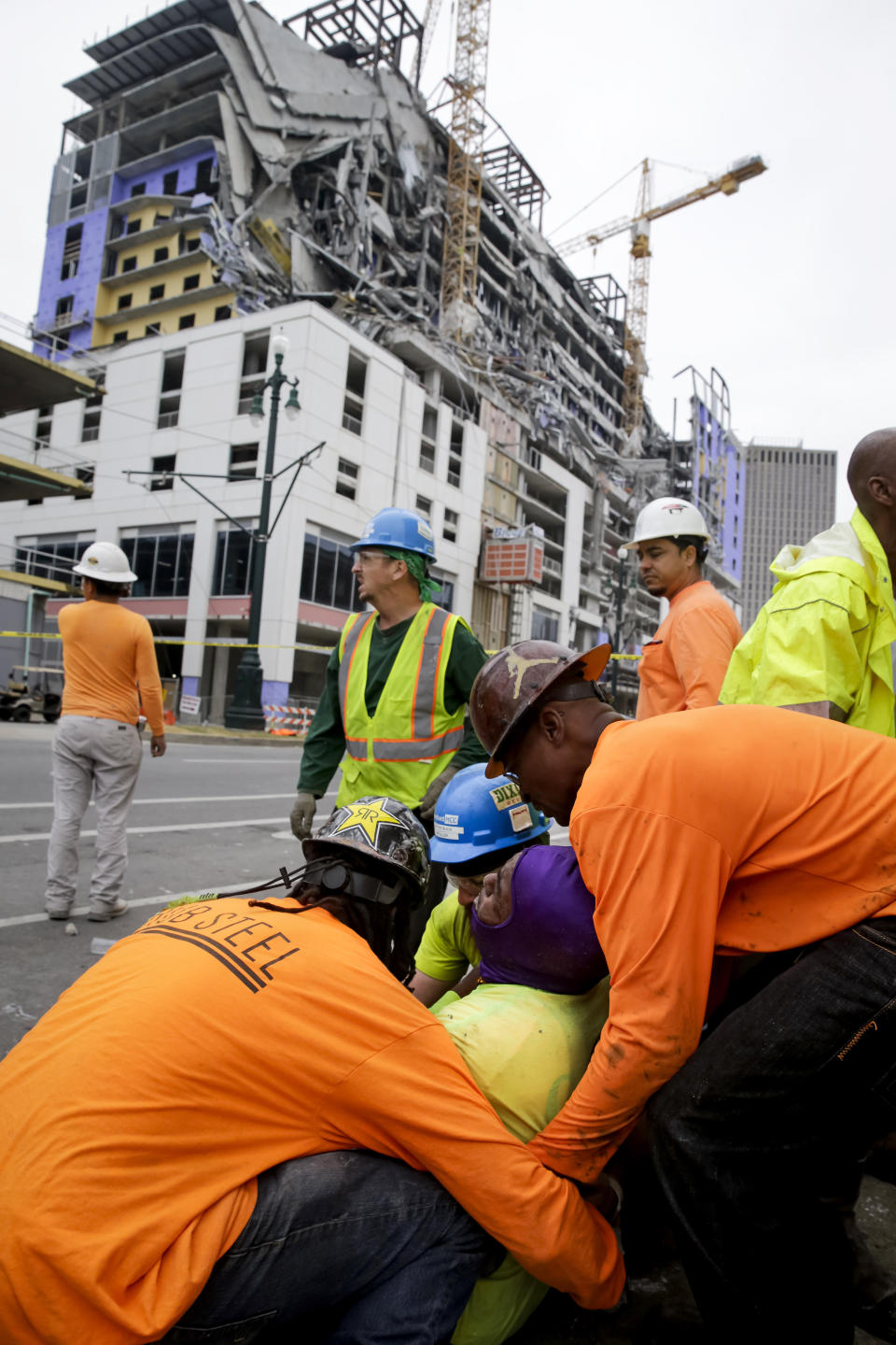 Workers are helped after a large portion of a hotel under construction suddenly collapsed in New Orleans on Saturday, Oct. 12, 2019. Several construction workers had to run to safety as the Hard Rock Hotel, which has been under construction for the last several months, came crashing down. It was not immediately clear what caused the collapse or if anyone was injured. (Scott Threlkeld/The Advocate via AP)