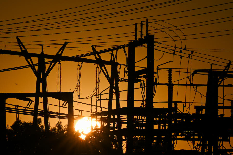 The sun sets behind a tangle of electric power lines.