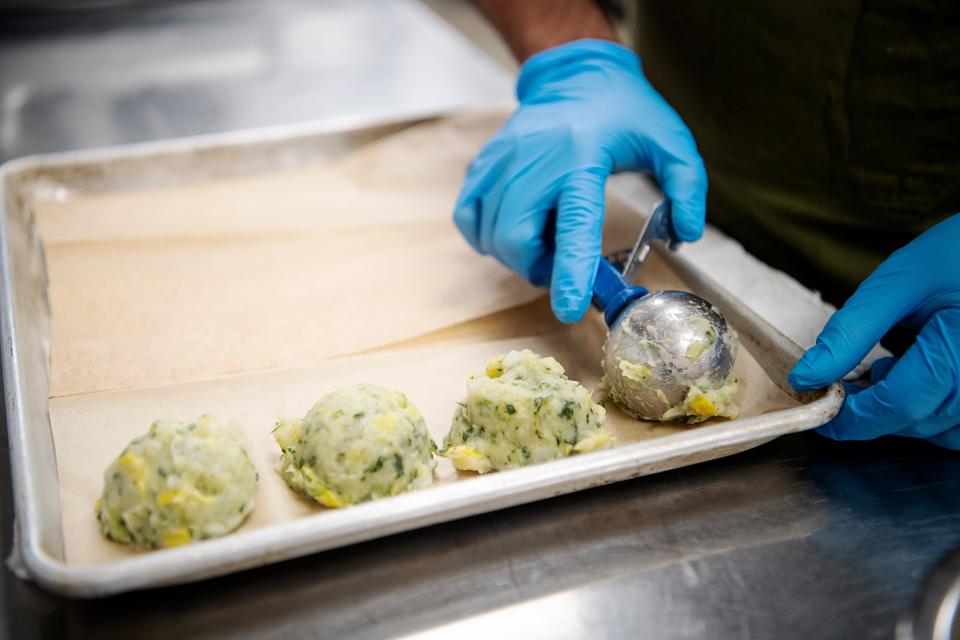 Chef Luis Martinez portions corn fritters with potato, spinach, masa and squash, February 22, 2024.