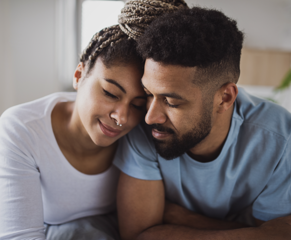 Two people affectionately leaning heads together, eyes closed, showing a moment of tenderness