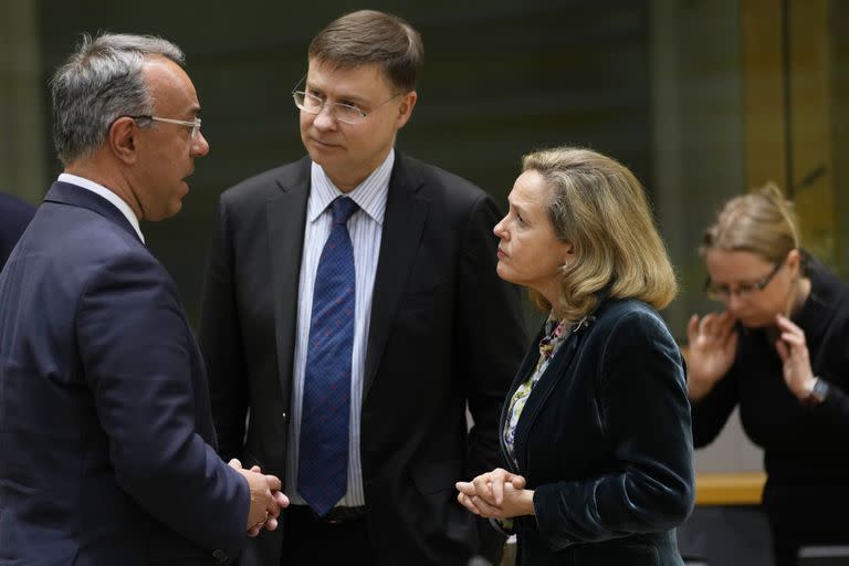 El comisario europeo de Economía y Hacienda, Valdis Dombrovskis, en el centro, habla con el ministro griego de Finanzas, Christos Staikouras, a la izquierda, y la ministra española de Economía, Nadia Calvino, durante una reunión de ministros de Finanzas de la eurozona en el edificio del Consejo Europeo en Bruselas, el lunes 13 de marzo de 2023.