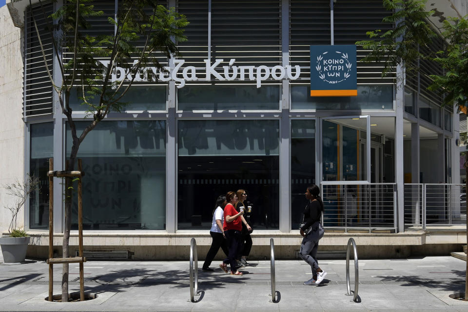 Women walk outside of a branch of Bank of Cyprus at a main shopping street in capital Nicosia in the eastern Mediterranean island of Cyprus, on Wednesday, June 7, 2023. When the U.S. and U.K. in April included a handful of Cypriot nationals and Cyprus-registered companies as part of another global crackdown on 'enablers' helping Russian oligarchs skirt sanctions, the perception that the island nation somehow remains Moscow's financial lackey again loomed large. (AP Photo/Petros Karadjias)