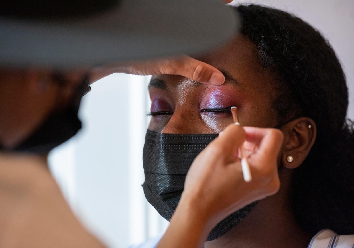 Latia Curtis applies eye makeup to Nanite Rogers.