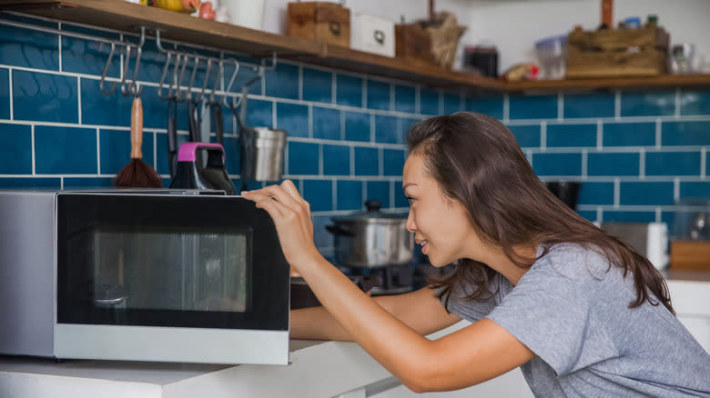 person putting food in microwave