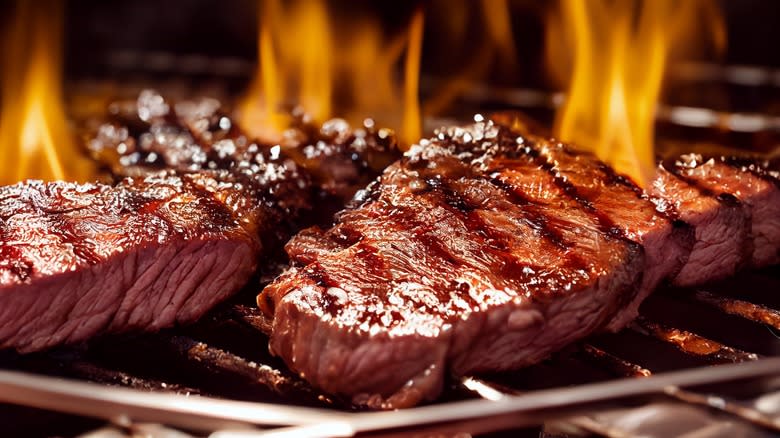 Steaks over flames of grill