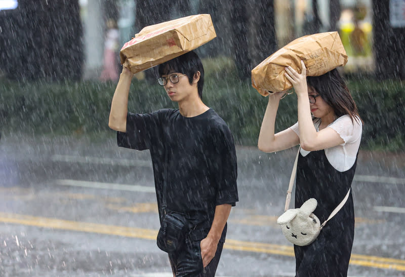 午後對流雲系發展旺盛  北市大雨（2） 受對流雲系發展旺盛影響，台北市信義區24日午後降 下大雨，沒有帶傘的民眾舉起手上物品遮雨，在大雨 中過馬路。 中央社記者鄭清元攝  113年6月24日 