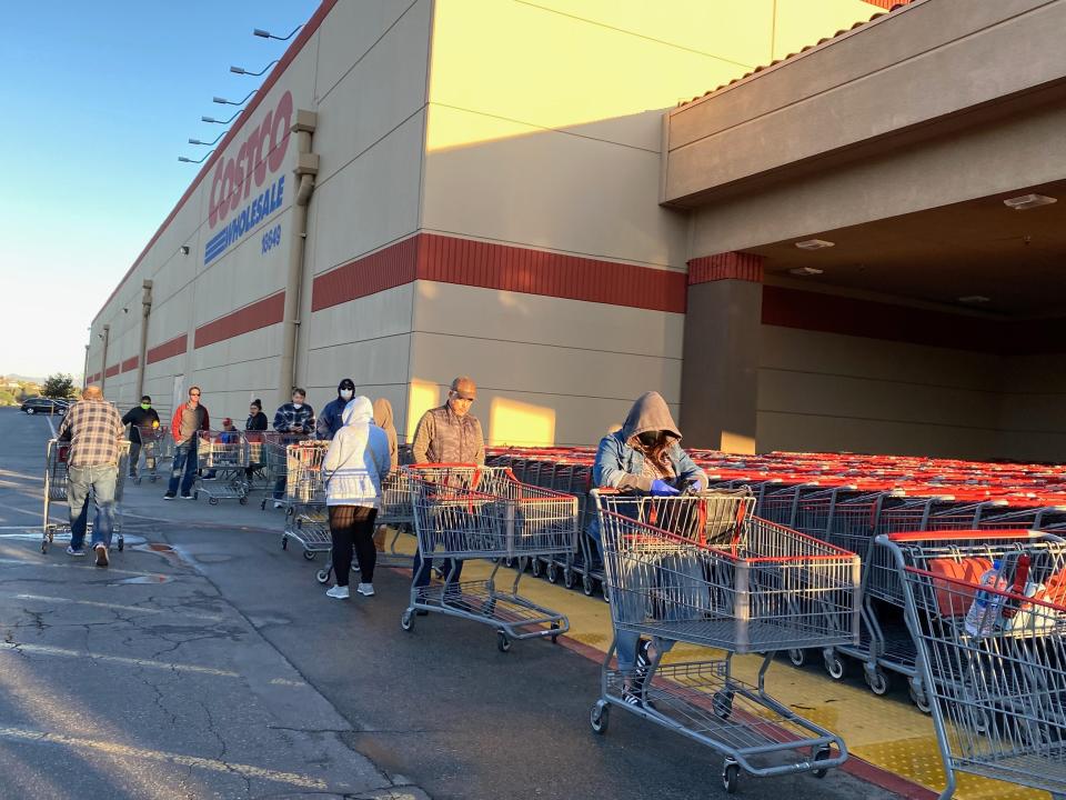 Customers lined up with carts outside of beige and red costco warehouse
