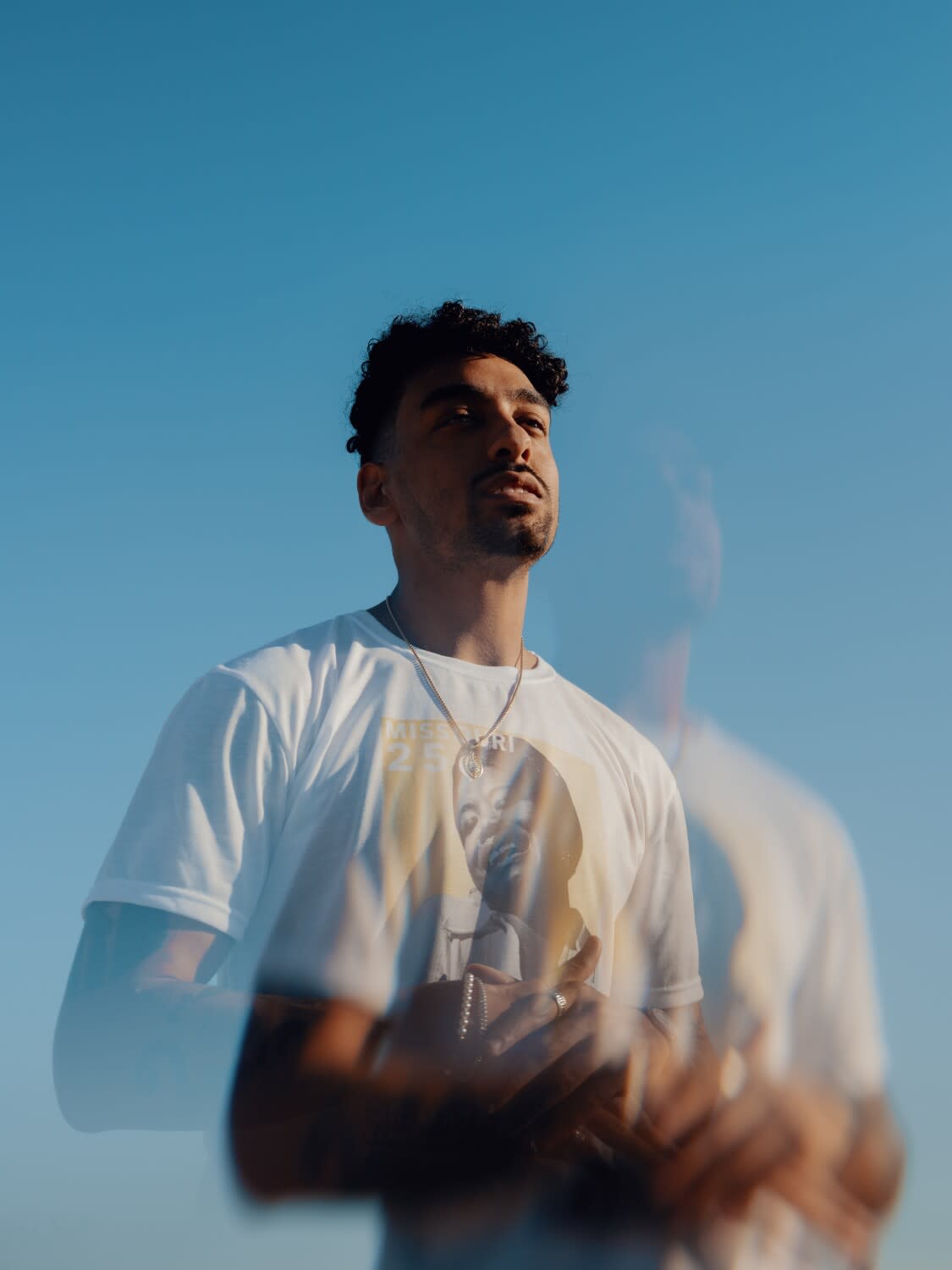 A portrait of a man in a white t-shirt.