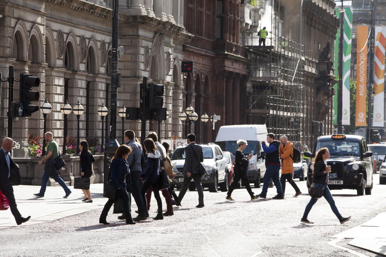 Commuters cross a downtown street during rush hour in Glasgow, Scotland