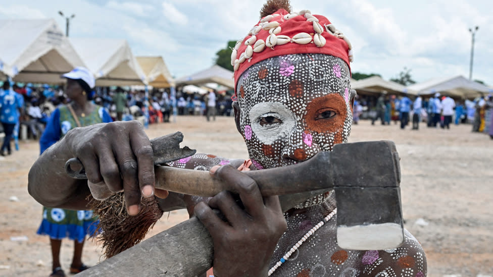 A supporter of Ivory Coast's ex-President Laurant Gbagbo with body paint decorations and an axe in Agboville, Ivory Coast - Saturday 6 April 2024