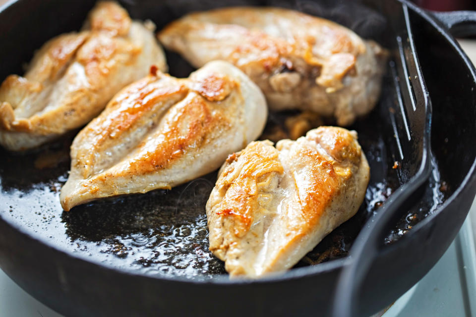 Fried chicken breasts in vegetable oil in a cast-iron pan